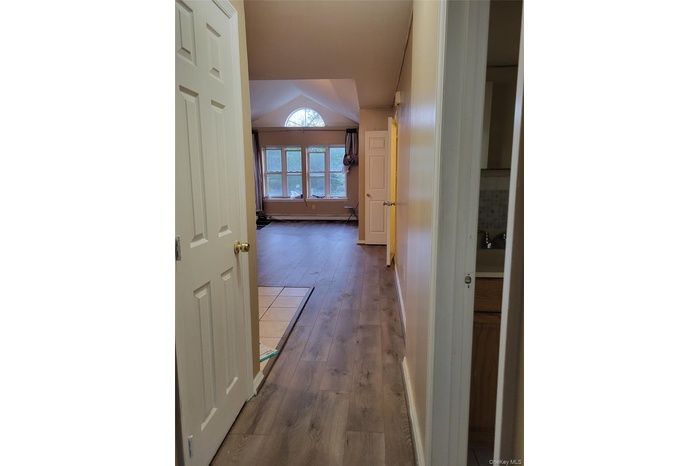 Hall featuring wood-type flooring, lofted ceiling, and a baseboard radiator
