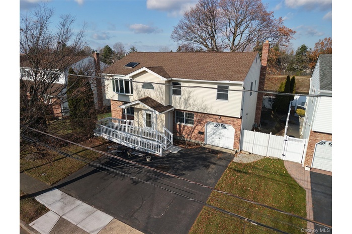 View of front of property featuring driveway, a chimney, brick siding, roof with shingles, and a garage