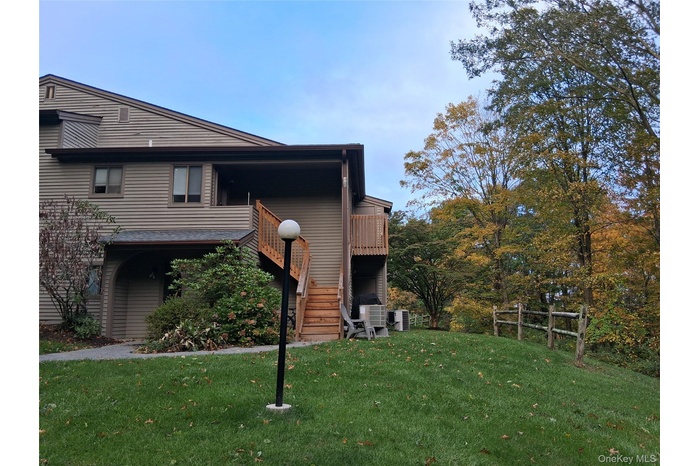 View of side of home featuring stairs, a lawn, and a deck