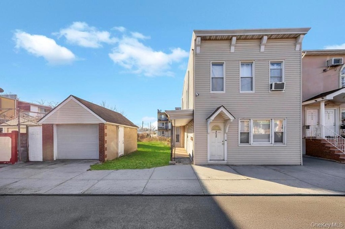 View of front of property featuring an outdoor structure, a detached garage, concrete driveway, and a front lawn