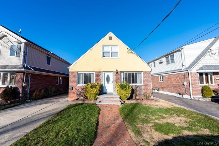 View of front of house featuring brick siding, a front yard, and stucco siding