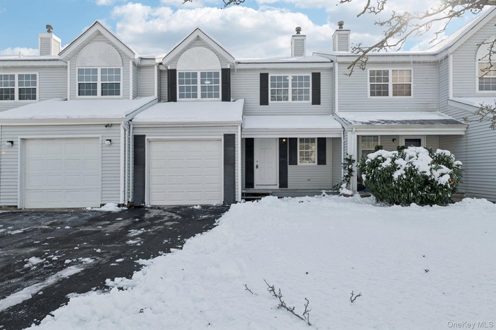 Traditional home with a chimney, a garage, asphalt driveway, and a porch
