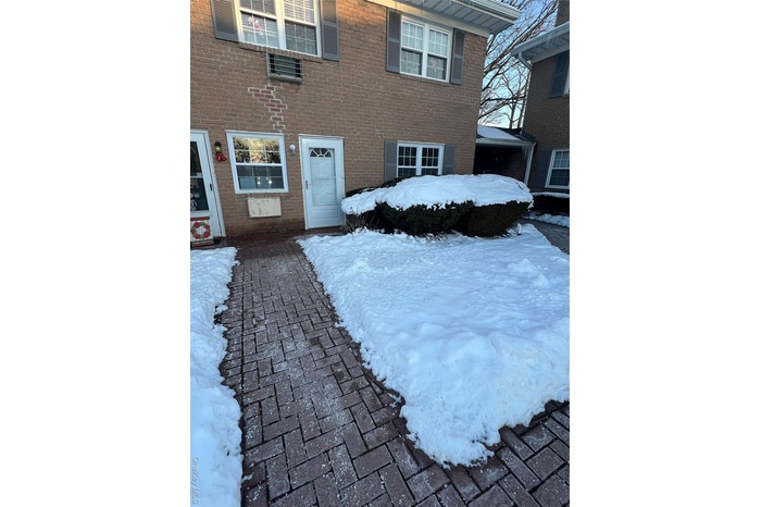 Snow covered property entrance with brick siding