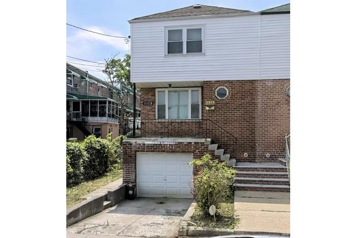 View of front facade featuring brick siding, driveway, a garage, and stairway