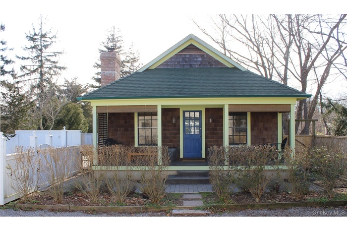 View of front facade with a porch, a chimney, and roof with shingles