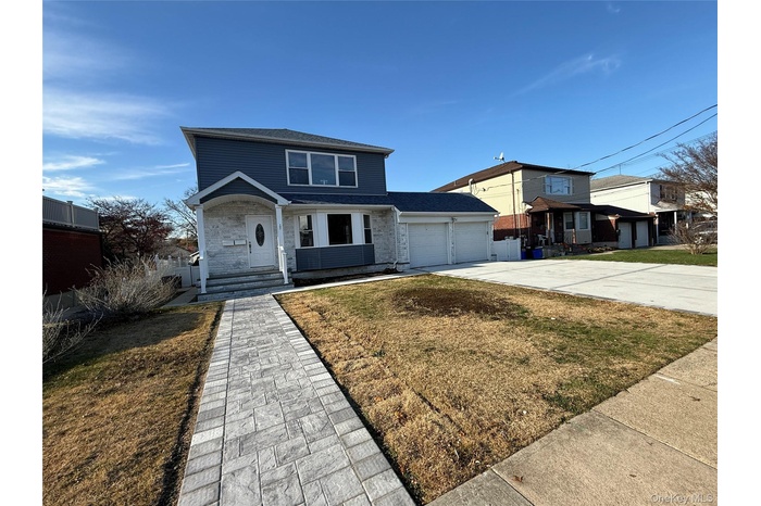 Traditional-style house featuring a front yard, concrete driveway, an attached garage, and a shingled roof