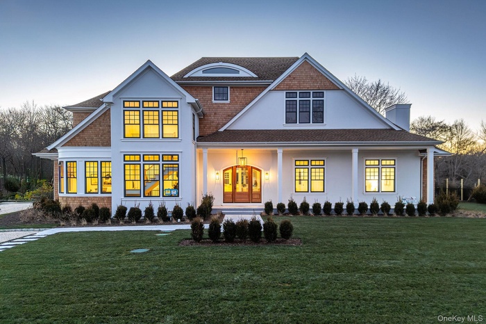 View of front facade featuring covered porch, a front lawn, a chimney, and stucco siding
