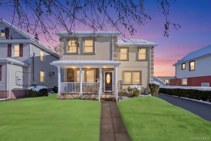 View of front of home with stucco siding, a porch, a front yard, a wall mounted air conditioner, and stone siding