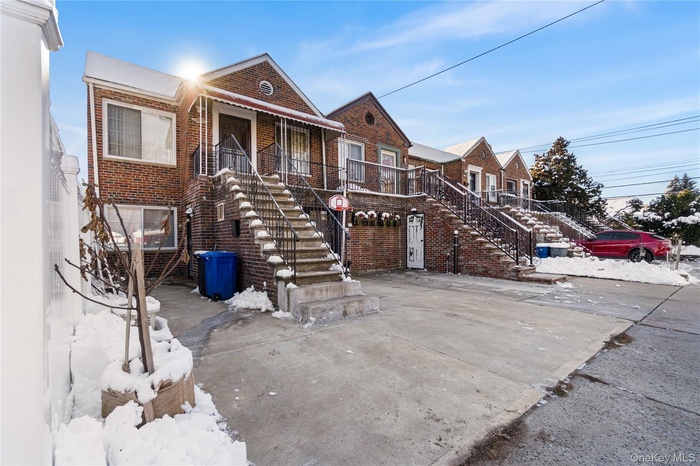 View of front of property featuring stairs, brick siding, and covered porch