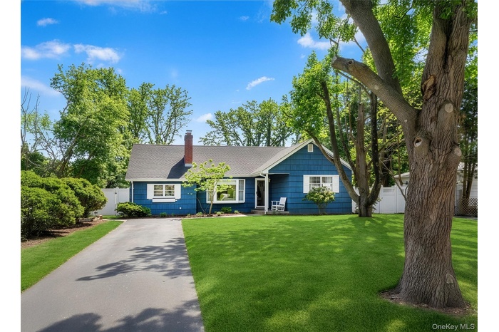 View of front of home with a shingled roof, a chimney, and asphalt driveway