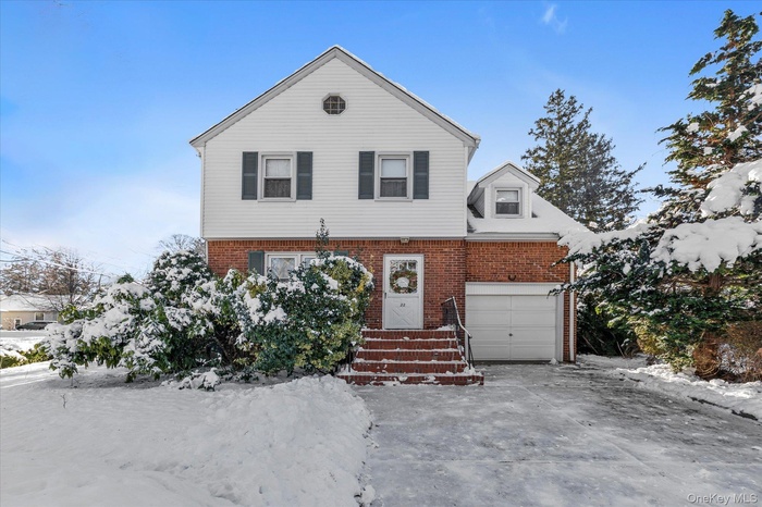 View of front of home featuring a garage, brick siding, and driveway