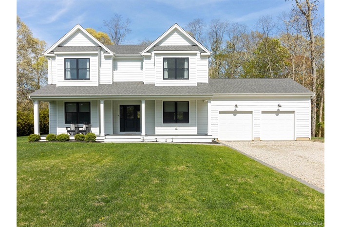 Traditional home with a porch, driveway, a front yard, roof with shingles, and an attached garage