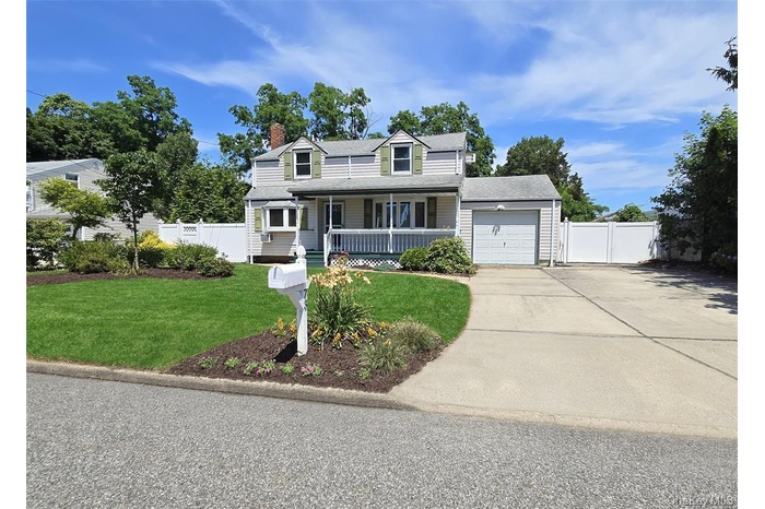 Cape cod home with a porch, concrete driveway, a garage, a chimney, and a gate