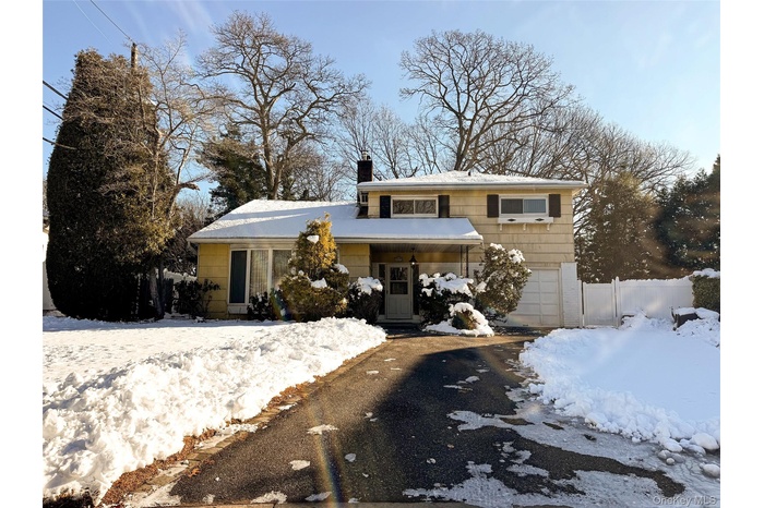 View of front of house featuring a chimney, a garage, and driveway