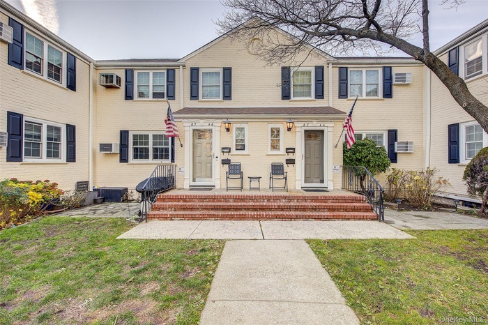 Traditional home with a front lawn, a patio, and a wall mounted AC