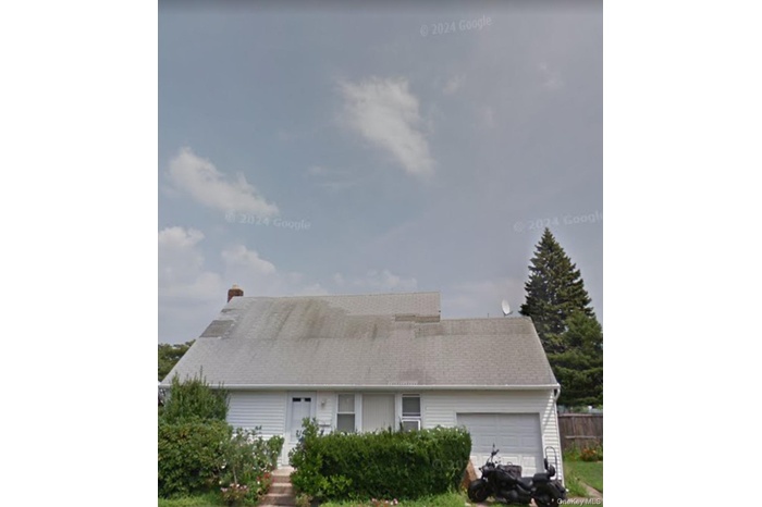 View of front facade featuring a garage and roof with shingles