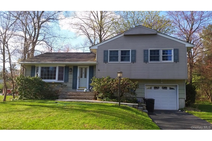 Split level home with a front yard, a garage, and asphalt driveway