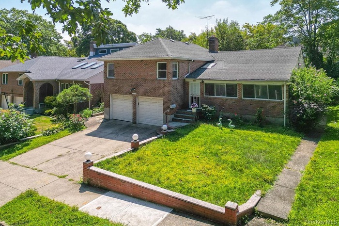 Tri-level home featuring brick siding, a front lawn, and a chimney