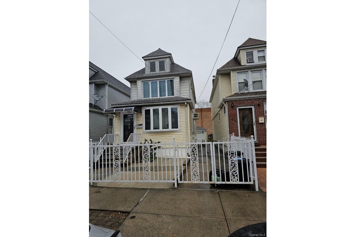 American foursquare style home with a fenced front yard, a gate, and roof with shingles