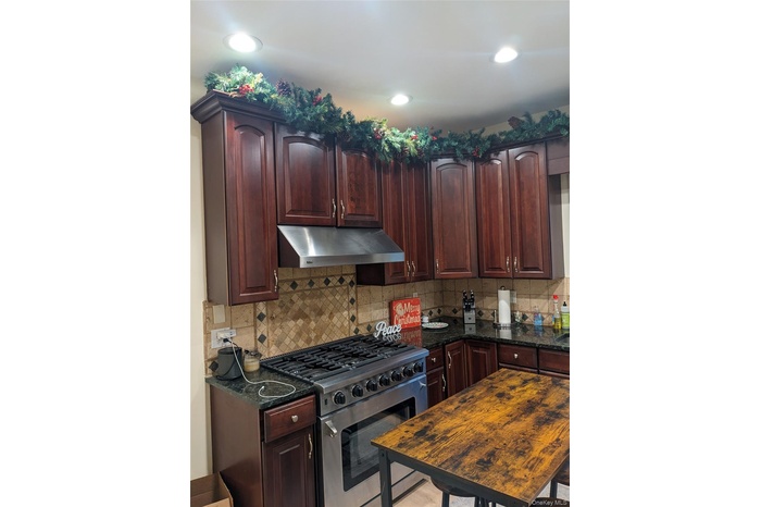 Kitchen featuring dark stone counters, high end stainless steel range, and tasteful backsplash