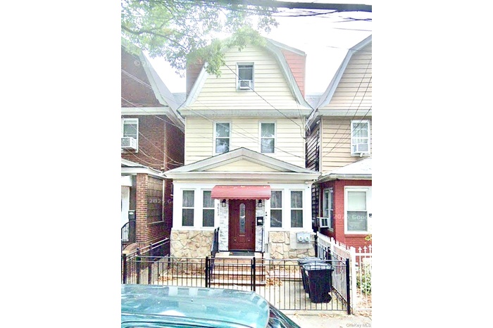 Colonial inspired home featuring stone siding, a fenced front yard, and a gambrel roof