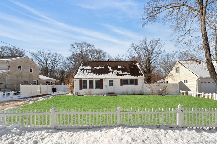 Cape cod-style house with roof with shingles, a chimney, and a fenced front yard