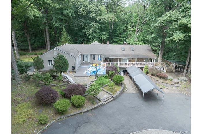 Rear view of house with a chimney, stairs, a deck, and a wooded view