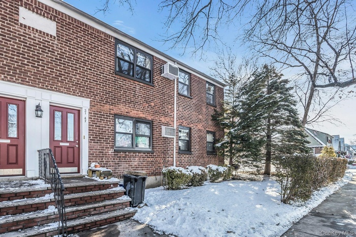 View of front of house with brick siding and a wall mounted AC