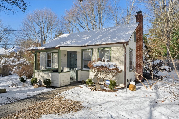 View of front of home featuring a chimney and covered porch