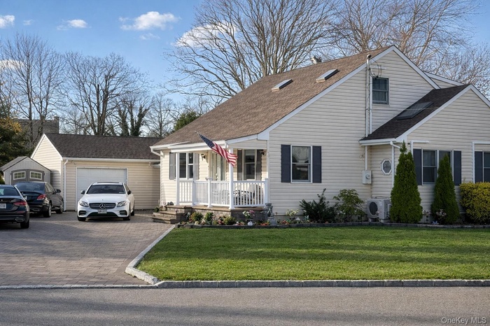 View of front of home with roof with shingles, a garage, decorative driveway, and a front lawn