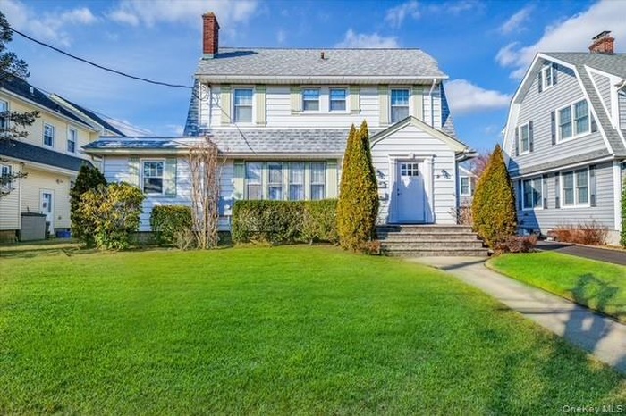 View of front of home with a chimney and a front yard