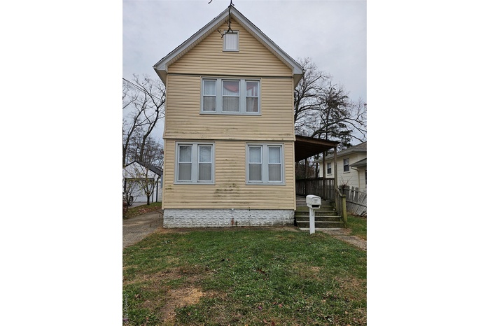 View of side of home featuring a lawn and covered porch