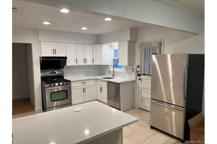 Kitchen with white cabinets, stainless steel appliances, light stone counters, tasteful backsplash, and recessed lighting