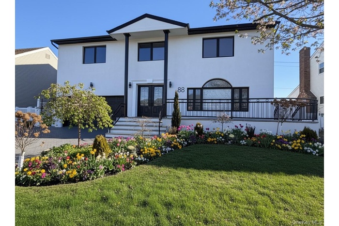 View of front of property with stucco siding, an attached garage, a front lawn, and french doors