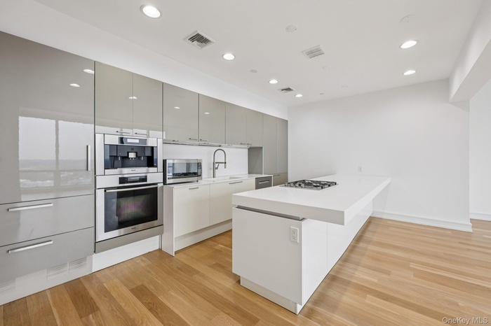 Kitchen with modern cabinets, a peninsula, appliances with stainless steel finishes, light wood-style flooring, and recessed lighting