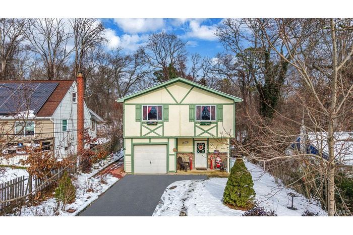View of front of property with stucco siding, asphalt driveway, a chimney, and an attached garage