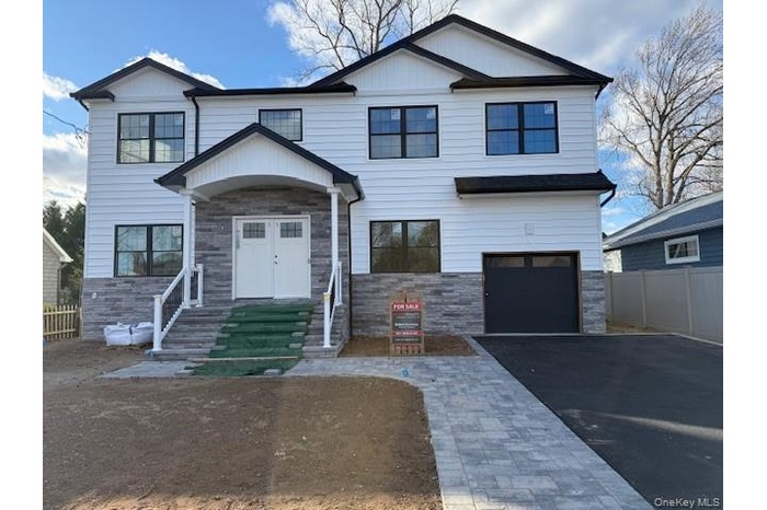 View of front of house featuring stone siding, a garage, and driveway