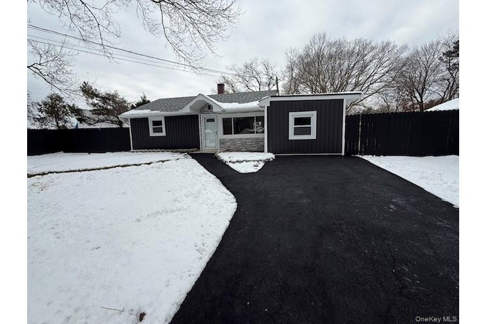 Snow covered back of property with a chimney