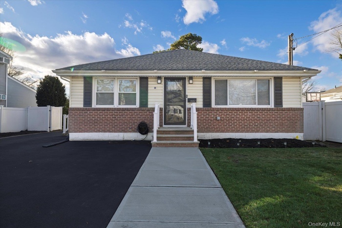 View of front of home with brick siding, roof with shingles, and a gate