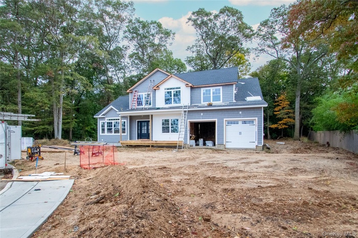View of front of home featuring view of wooded area, a deck, a shingled roof, and a garage