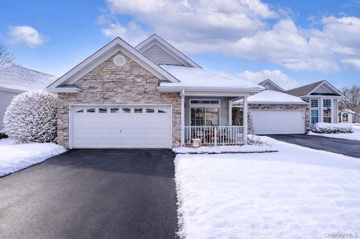 Ranch-style house with asphalt driveway, a porch, stone siding, and a garage