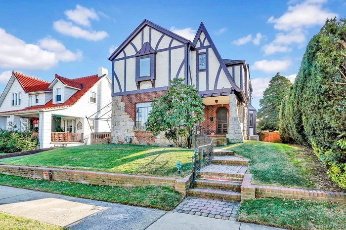 Tudor home with brick siding, stucco siding, and covered porch