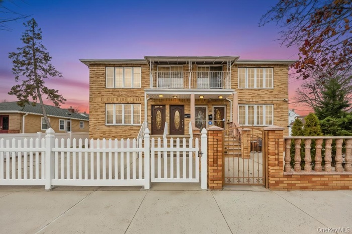 Traditional-style home featuring a gate, a fenced front yard, and a balcony