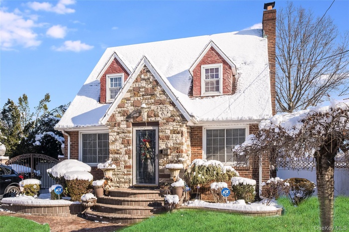 View of front of house with a gate, brick siding, a chimney, and stone siding