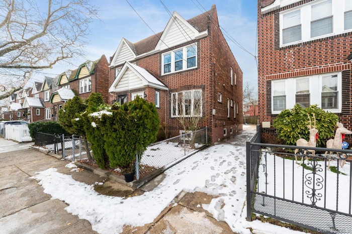 View of front of house featuring a residential view, brick siding, a fenced front yard, and a gate