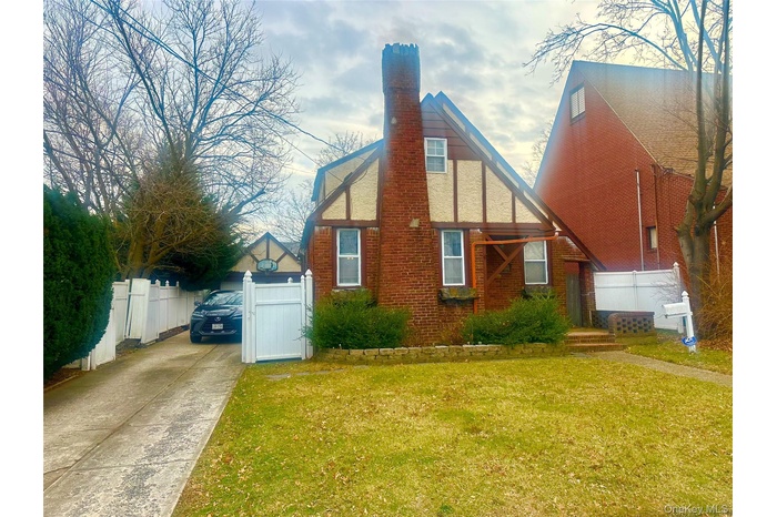 View of property exterior featuring a chimney and concrete driveway