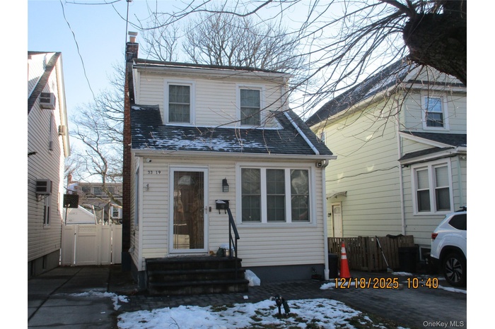 View of front of house featuring a chimney, a shingled roof, and a gate
