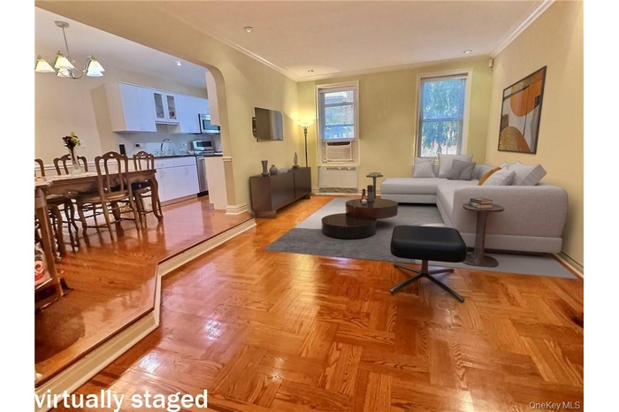 Living area featuring arched walkways, ornamental molding, radiator heating unit, and a chandelier