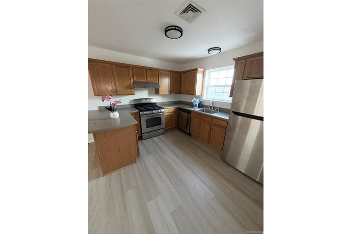 Kitchen featuring stainless steel appliances, brown cabinets, and a peninsula