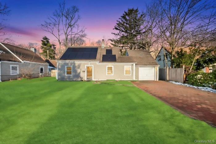 View of front facade with solar panels, decorative driveway, and a garage